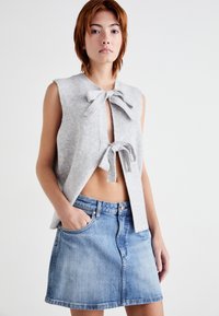 Sivi rebrasti pleteni cropped top z dvema sprednjima mašnjama, v kombinaciji z jasno modrim denim krilom, ki ima sprednje gumbe in žepke.