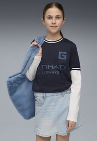 Marine T-shirt med hvide accenter og Etihad Airways logo, lagd ovenpå en hvid langærmet top. Denim nederdel med slidte detaljer og blød blå taske.