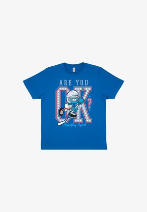 T-shirt bleu avec un joueur de hockey en dessin animé portant un casque et des patins, texte « Ça va ? » et « Esprit Schtroumpf » sous de grandes lettres décorées OK.