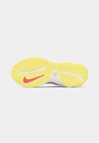 Nike sportcipő talpa sárga gumiból készült, textúrázott talprajzokkal és rózsaszín Nike pipa akcentussal.