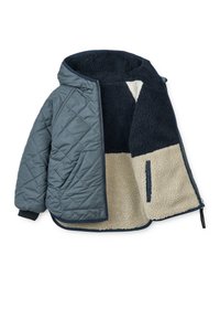 Giacca puffer trapuntata con uno strato esterno blu navy e foderato in pelliccia sintetica color crema, che presenta un design a blocchi di colore e tasche laterali.