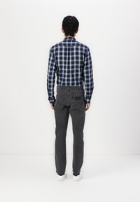 Blue and white plaid button-up shirt paired with gray jeans. Shirt features a collar; jeans have back pockets and a textured finish.