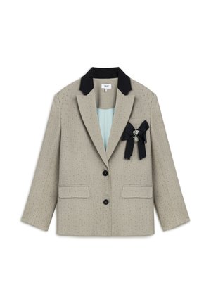 Beige blazer met zwarte kraag, twee voorkoeken en een decoratieve broche. Heeft een subtiele pin-dot textuur en sluit met een enkele knop.