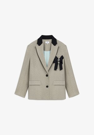 Beige Blazer mit schwarzem Kragen, zwei vorderen Taschen und einer dekorativen Brosche. Verfügt über eine subtile Punktstruktur und einen einreihigen Knopfverschluss.