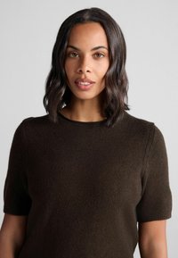 Brun kortærmet sweater lavet af blødt strikket materiale. Har en rund halsudskæring og en subtil tekstur, hvilket giver et afslappet udseende.