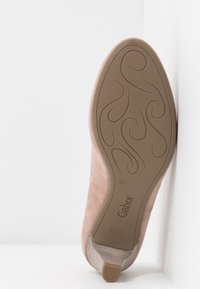Chaussure en daim rose avec une semelle en caoutchouc texturée, présentant un motif de bande de roulement incurvé et un petit talon, étiquetée "Gabor" et taille 4½.