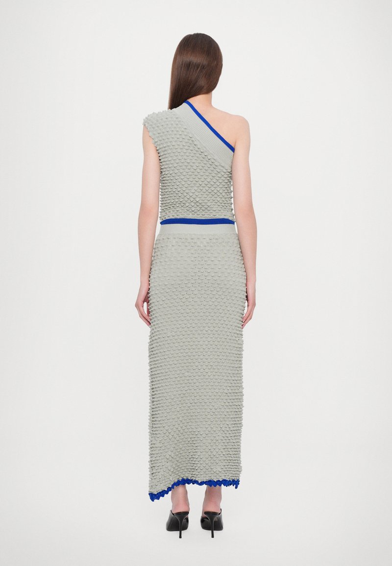 Vestido gris texturizado con diseño de un solo hombro, que presenta una banda de acento azul en la cintura y un dobladillo ondulado. Silueta suave y ajustada.