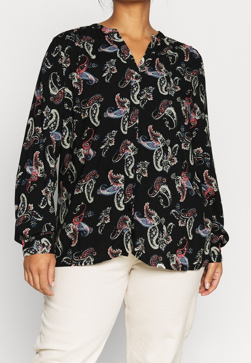 Black blouse with a paisley pattern in red, white, and blue. Features a V-neck and long sleeves with buttoned cuffs. Made from lightweight fabric.