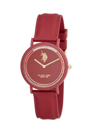 Orologio da polso rosso U.S. Polo Assn. con lancette dorate, logo del giocatore di polo, accenti di cristalli rossi e rosa intorno al quadrante e cinturino in silicone.