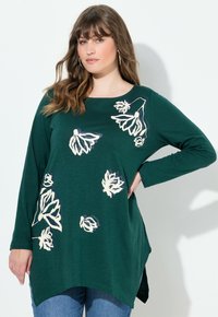 Grünes langärmliges Oberteil mit blumigen Mustern in Beige und Weiß. Weicher Stoff mit rundem Ausschnitt und seitlichen Schlitzen für mehr Bewegungsfreiheit.