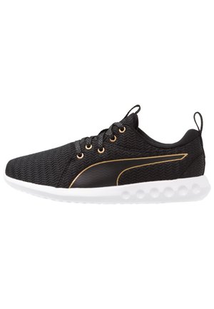 Sort atletiksneaker med tekstureret stof, guldfarvede huller til snørebånd og pynt, hvid polstret sål samt trækflapper på tunge og hæl.