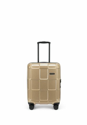 Valise rigide dorée avec quatre roues noires pivotantes et poignée télescopique étendue, marquée "Epic" à l'avant.