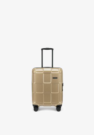 Valise rigide dorée avec quatre roues noires pivotantes et poignée télescopique étendue, marquée "Epic" à l'avant.