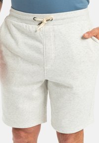 Šedé šortky ze svetroviny vyrobené z měkké látky, s elastickým pasem, šňůrkou, dvěma bočními kapsami a hladkým povrchem.