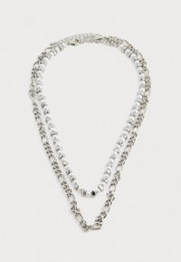 Collier superposé en argent métallique avec des chaînes et des accents de perles blanches, affichant un mélange de finitions lisses et texturées.