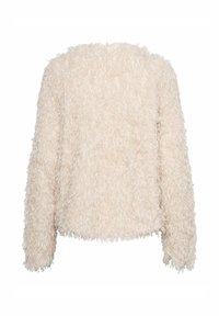 Faux bontjas in zacht beige met een gestructureerd, pluizig oppervlak en lange mouwen; heeft een boxy silhouet en een ronde hals.