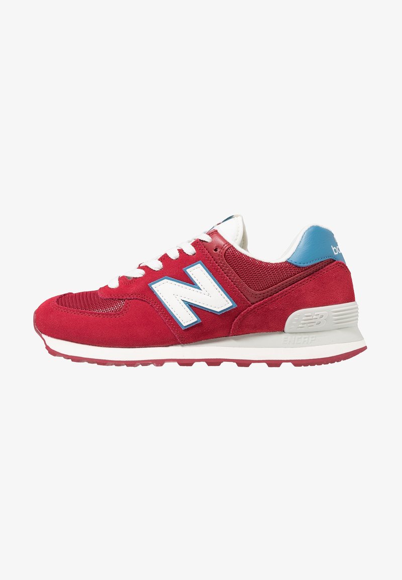 Baskets rouges New Balance avec lacets blancs, languette bleue au talon et logo blanc "N" bordé de bleu, présentées de profil sur fond blanc.