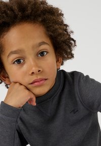 Grauer Langarm-Pullover mit strukturiertem Material und rundem Halsausschnitt, versehen mit einem kleinen gestickten Logo auf der Brust.