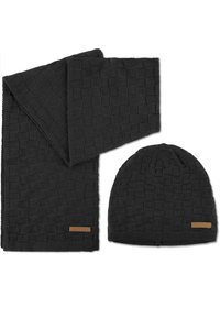 Schwarzes Strickmützen- und Schalsset mit einem strukturierten Schachbrettmuster. Beide Artikel haben ein dezentes Logo-Detail aus braunem Leder.