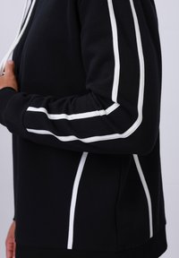 Zwarte hoodie van een katoenmix, met witte strepen langs de mouwen en zijkanten, een gestructureerde pasvorm en geribde manchetten.