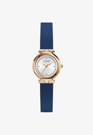 Roze gouden horloge met een met kristallen versierde wijzerplaat en een blauwe siliconen band, met het merk "GUESS" op de wijzerplaat.