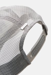 Grå mesh-cap med en strukturell design, som har en sølv-logo aksent og en plastjusterbar stropp på baksiden.