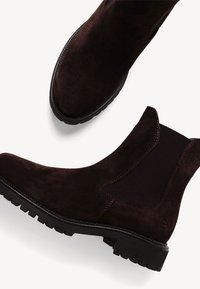 Botines de ante marrón con inserciones elásticas en los laterales, suela de goma texturizada, punta redondeada y detalles de costura en contraste.