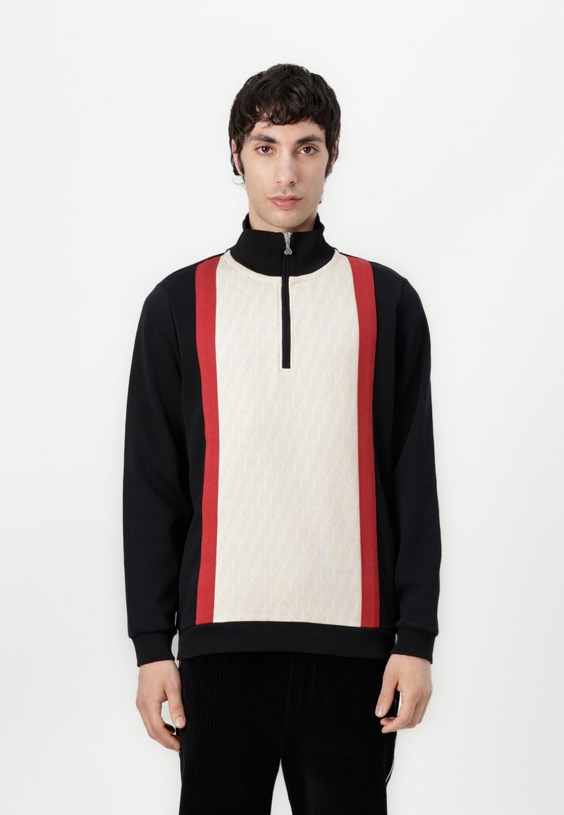 Schwarze und cremefarbene Zip-Hoodie mit einer strukturierten cremefarbenenplatte mit roten Streifen, hohem Kragen und gerippten Bündchen. Glatte Stoffoberfläche.
