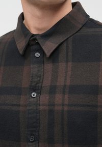 Károvaná košeľa v tmavých tónoch, so zapínaním na gombíky, špicatým golierom a textúrovanou látkou. Čierne, hnedé a sivé farby s jemnými pásikmi.