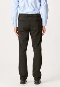Sorte dressbukser med en glat tekstur, lige skæring og to baglommer. Båret med en lyseblå button-up skjorte.