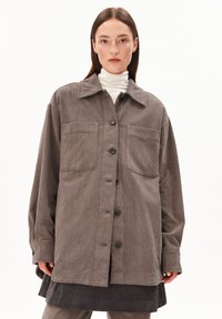 Braune Kordjacke mit spitzem Kragen, vorderem Knopfverschluss und zwei Brusttaschen. Sie hat einen lässigen Schnitt und ein strukturierte Material.