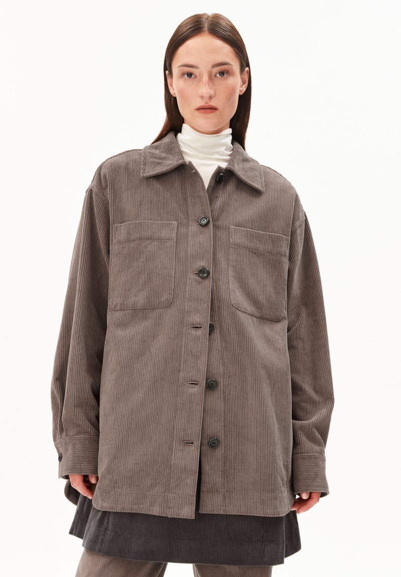 Braune Kordjacke mit spitzem Kragen, vorderem Knopfverschluss und zwei Brusttaschen. Sie hat einen lässigen Schnitt und ein strukturierte Material.