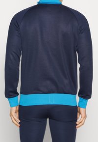 Marinblå sweatshirt med blå krage och muddar. Tillverkad av mjukt tyg, den har ribbade detaljer och en åtsittande design för komfort.
