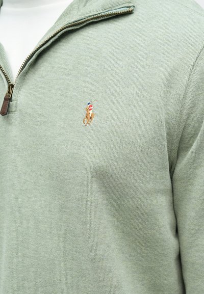 Ανοιχτό πράσινο φούτερ με φερμουάρ, κατασκευασμένο από υφασμάτινη υφή, με μικρό κεντημένο λογότυπο αλόγου και φερμουάρ από καφέ δέρμα.