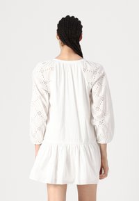 Rochie albă din bumbac cu mâneci bufante, prezentând detalii de broderie anglaise, talie strânsă și tiv freati, evazat.