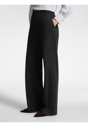 Black wide-leg trousers made of a smooth fabric, featuring a high waist and side pockets. Paired with a striped blouse and pointed shoes.
