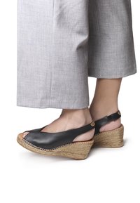 Svarta lädersandaler med kilklack och öppen tådesign. Jutewrapad kilklack, justerbart vristband och öppen häl.