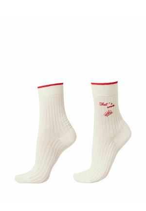 Chaussettes blanches côtelées à col montant avec bordure rouge, une chaussette affiche un texte rouge "That's amore" et un petit motif de tranche de pizza.
