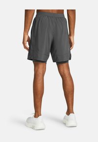 Pantalones cortos atléticos grises hechos de una tela ligera, con una cinturilla elástica y un ajuste holgado, con acentos laterales negros.
