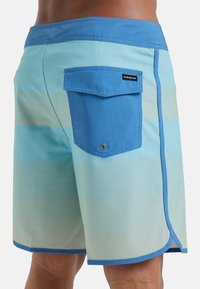 Blaue und hellblaue Boardshorts mit horizontalen Streifen, einer Gesäßtasche mit Klappe und kontrastierenden Nähten entlang der Kanten.