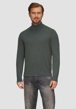 Donkergroen coltrui van gebreid materiaal, met lange mouwen en een aansluitend design. Gerged met lichtgrijze jeans.