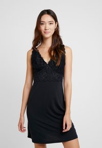 Svart ärmlös klänning med en spetslivstycke med scallopkanter och ett mjukt, slätt nederdels-tyg. Faller lätt vid sidorna.