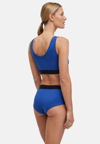 Blauer Baumwoll-Sport-BH und passende Unterhose mit einem schwarzen Gummibund, die ein schlichtes Design und eine glatte Textur aufweisen.
