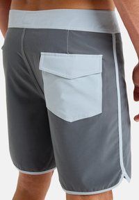Men's swim shorts in dark gray with light gray accents. Features a rear pocket with a flap and contrasting stitching. Smooth, lightweight material.