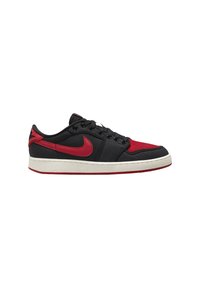 Sneaker basso nero e rosso con swoosh Nike rosso, lacci neri e suola bianca su sfondo bianco, vista laterale.