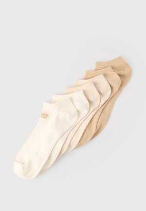 Seks par ankel-sokker arrangert i en gradient fra krem til lys brun på en lys grå bakgrunn.