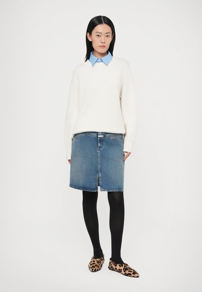 Krém színű pulóver, világoskék galléros ing, sötét farmer szoknya, fekete harisnya és leopárdmintás cipők. Anyag: kötött, farmer és puha anyag.