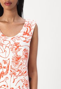 Weißes, geripptes Tanktop mit auffälligen orangen Blumendrucken und Rundhalsausschnitt, das sich auf eine enganliegende Passform und weiche Textur konzentriert.