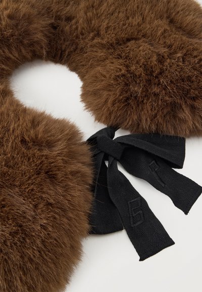 Col en fourrure marron duveteuse avec fermeture à nouer en tissu noir sur une surface blanche, montrant la texture et le détail de la fixation.