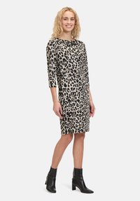 Leopardmuster-Kleid mit Dreiviertelärmel, beige und schwarz, gerader Schnitt und kombiniert mit schwarzen Stiefeletten.
